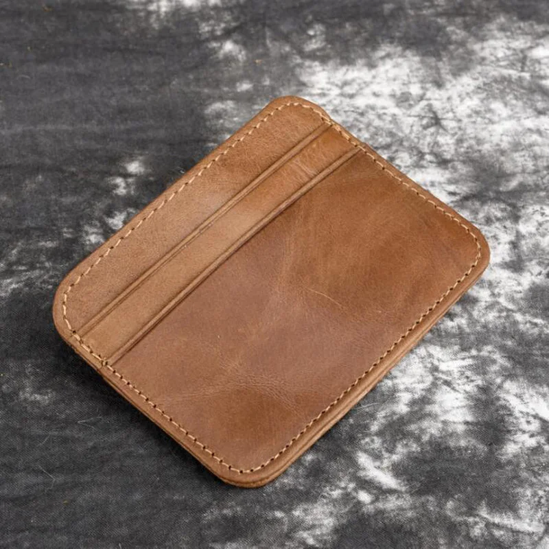 tan leather wallet sitting on a gray surface, possibly a table or a counter. The wallet appears to be handmade and has a brown color with a tan finish.tanneur porte carte